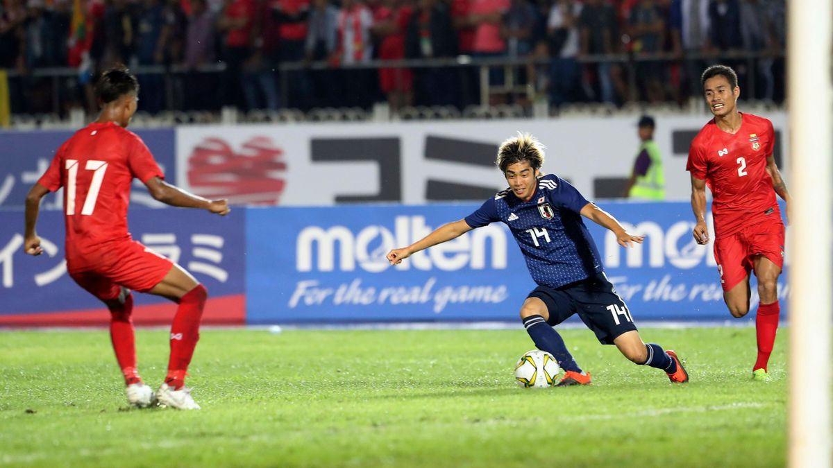 Japan’s  Ito  Junya,  center,  vies  for  the  ball  with  Myanmar’s  Soe  Moe  Kyaw,  left,  and  Zaw  Lin,  right,    qualifying  soccer  match  in  Yangon,  Myanmar, in 2019.