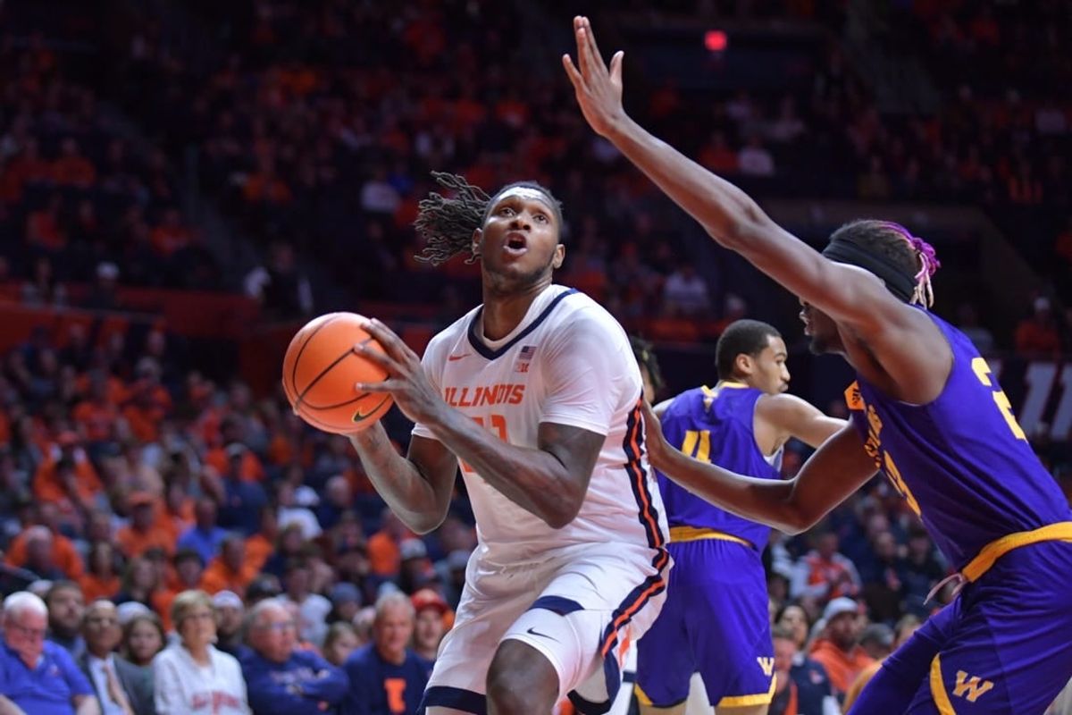 Nov 24, 2023; Champaign, Illinois, USA;  Illinois Fighting Illini forward Dain Dainja (42) drives to the basket as Western Illinois Leathernecks center Drew Cisse (23) defends during the first half at State Farm Center.