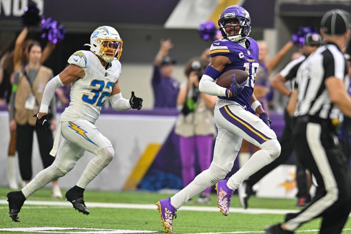 Sep 24, 2023; Minneapolis, Minnesota, USA; Minnesota Vikings wide receiver Justin Jefferson (18) scores on a touchdown pass as Los Angeles Chargers safety Alohi Gilman (32) chases from behind during the fourth quarter at U.S. Bank Stadium.