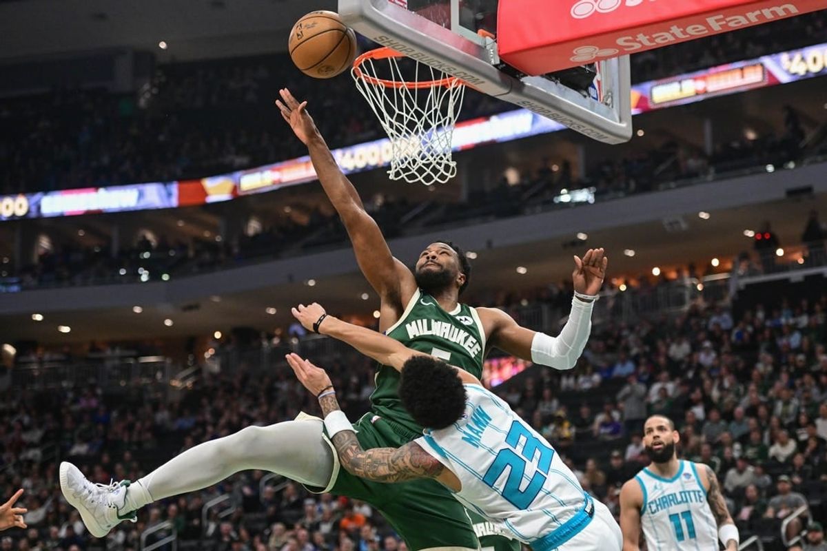 Feb 27, 2024; Milwaukee, Wisconsin, USA;  Milwaukee Bucks guard Malik Beasley (5) takes a shot against Charlotte Hornets guard Tre Mann (23) in the first quarter at Fiserv Forum.