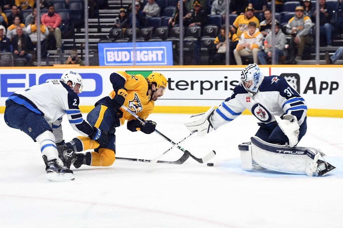 Apr 9, 2024; Nashville, Tennessee, USA; Nashville Predators center Tommy Novak (82) skates past Winnipeg Jets defenseman Dylan DeMelo (2) before scoring against goaltender Connor Hellebuyck (37) during the first period at Bridgestone Arena.