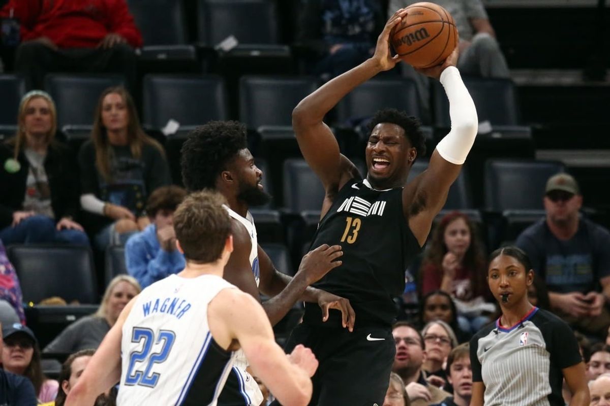 Jan 26, 2024; Memphis, Tennessee, USA; Memphis Grizzlies forward-center Jaren Jackson Jr. (13) collects a rebound over Orlando Magic forward Jonathan Isaac (1) during the first half at FedExForum.