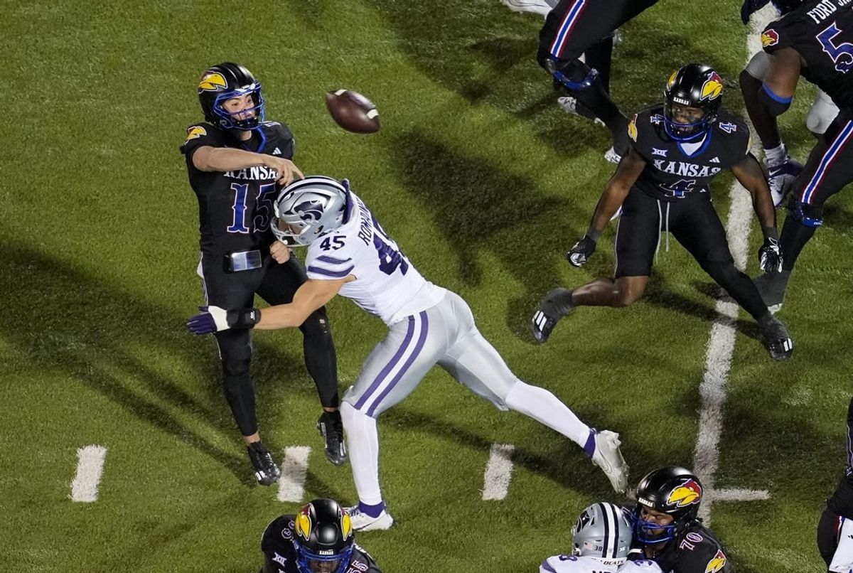 Nov 18, 2023; Lawrence, Kansas, USA; Kansas Jayhawks quarterback Cole Ballard (15) throws a touchdown pass as he is hit by Kansas State Wildcats linebacker Austin Romaine (45) during the first half at David Booth Kansas Memorial Stadium.