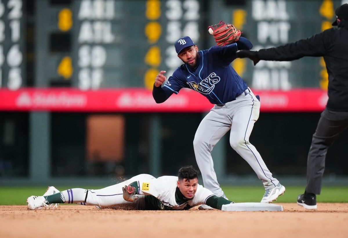 Apr 6, 2024; Denver, Colorado, USA; Colorado Rockies shortstop Ezequiel Tovar (14) slides safe under Tampa Bay Rays outfielder Amed Rosario (10) the sixth inning at Coors Field.