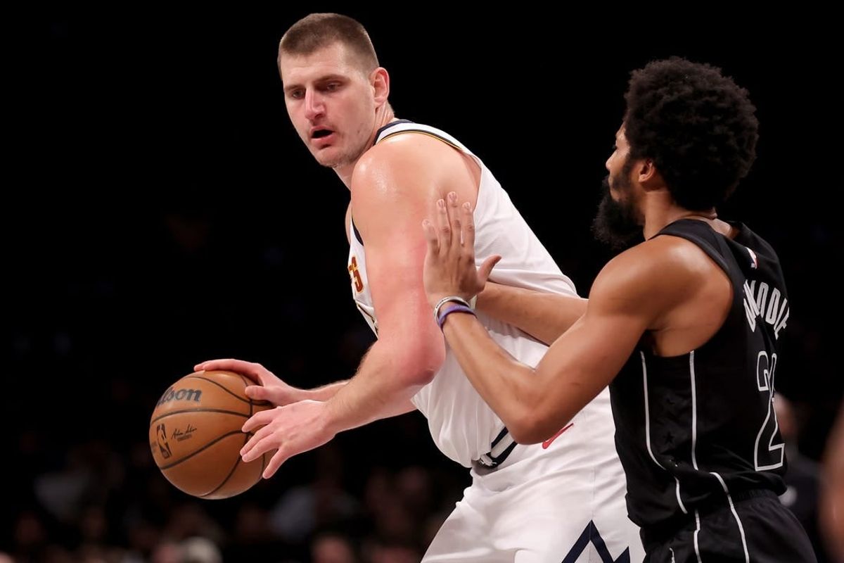 Dec 22, 2023; Brooklyn, New York, USA; Denver Nuggets center Nikola Jokic (15) controls the ball against Brooklyn Nets guard Spencer Dinwiddie (26) during the second quarter at Barclays Center.