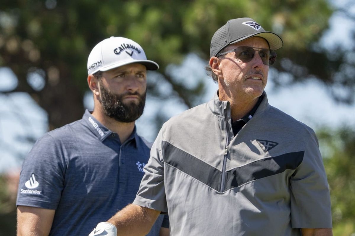 July 19, 2023; Hoylake, ENGLAND, GBR; Jon Rahm (left) watches the tee shot of Phil Mickelson (right) on the 18th hole during a practice round of The Open Championship golf tournament at Royal Liverpool.