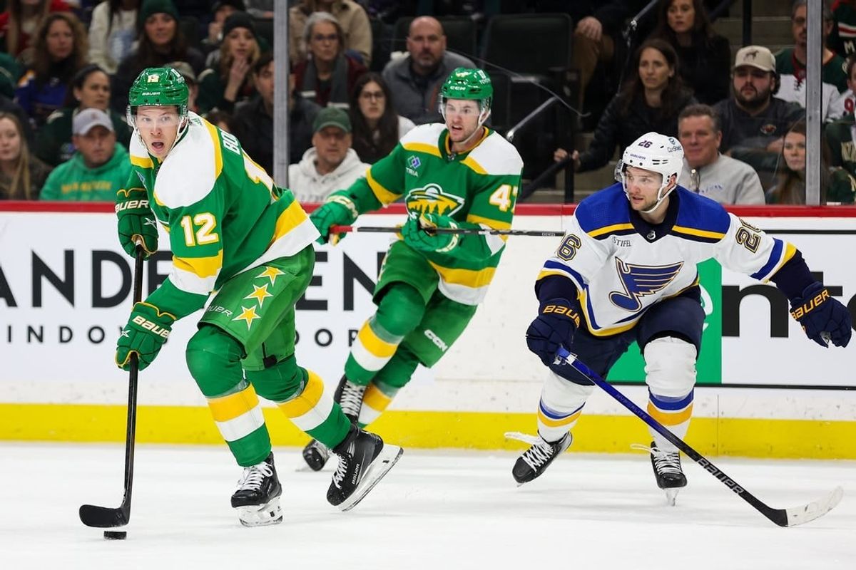 Mar 23, 2024; Saint Paul, Minnesota, USA; Minnesota Wild left wing Matt Boldy (12) skates with the puck as St. Louis Blues left wing Nathan Walker (26) defends during the third period at Xcel Energy Center.