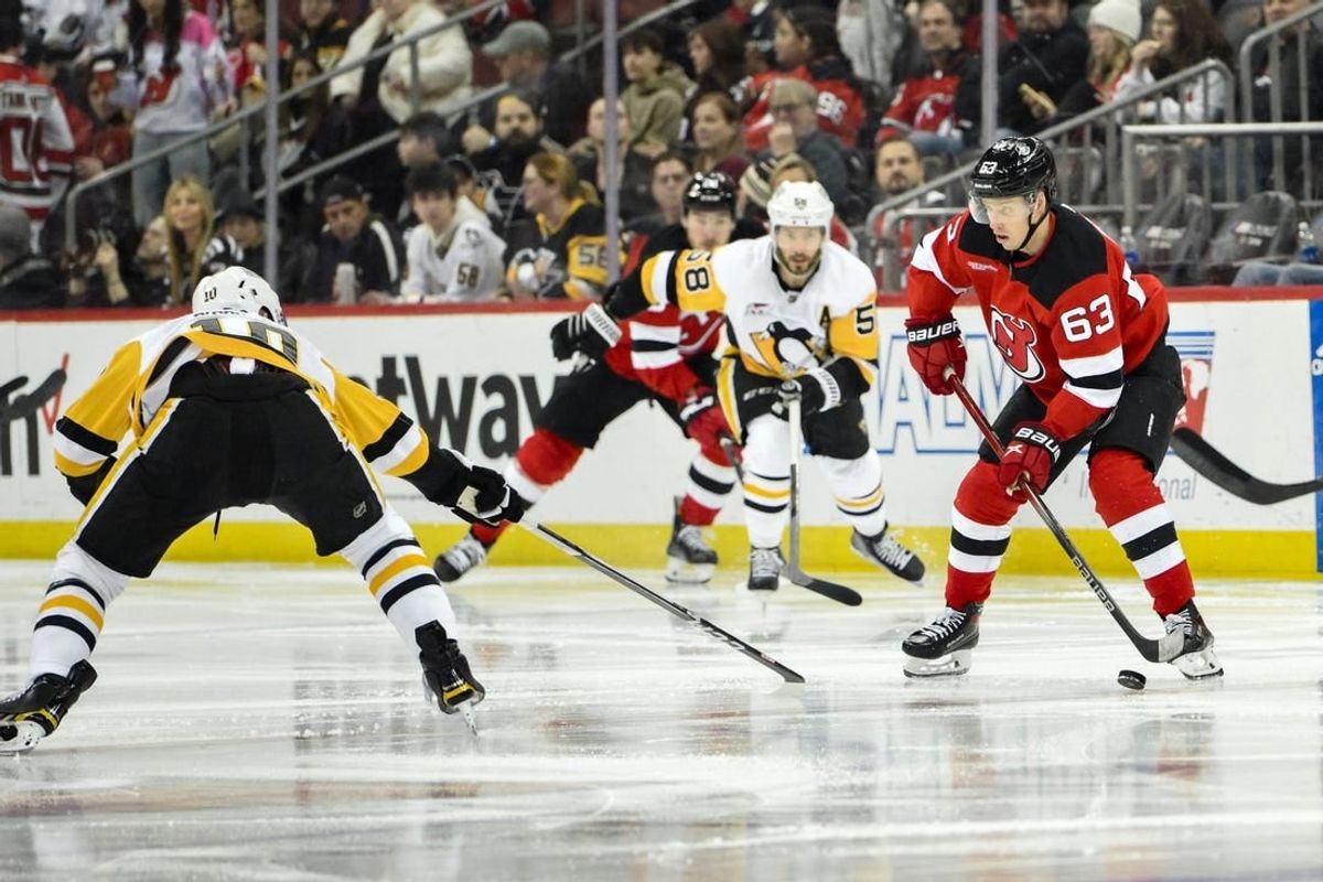 Apr 2, 2024; Newark, New Jersey, USA; New Jersey Devils left wing Jesper Bratt (63) skates with the puck while being defended by Pittsburgh Penguins left wing Drew O'Connor (10) and Pittsburgh Penguins defenseman Ryan Shea (5) during the second period at Prudential Center.