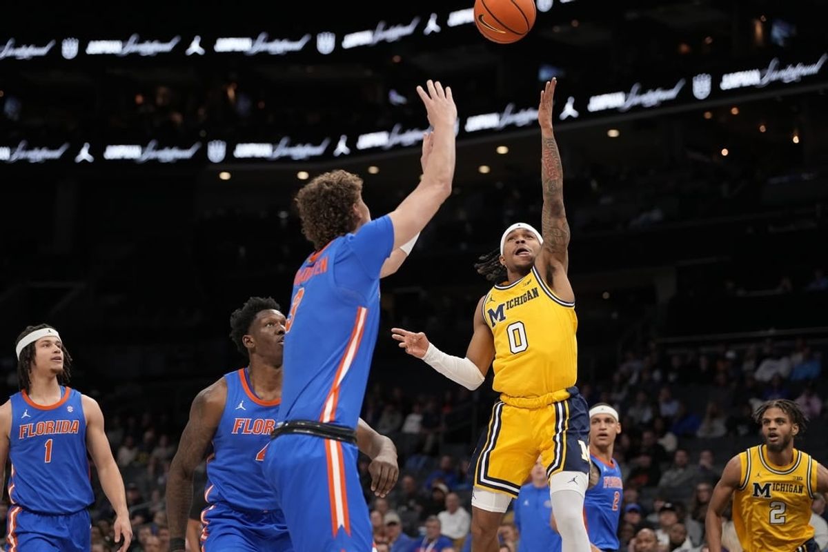 Dec 19, 2023; Charlotte, North Carolina, USA; Michigan Wolverines guard Dug McDaniel (0) goes up for a shot defended by Florida Gators center Micah Handlogten (3) during the first half at Spectrum Center.