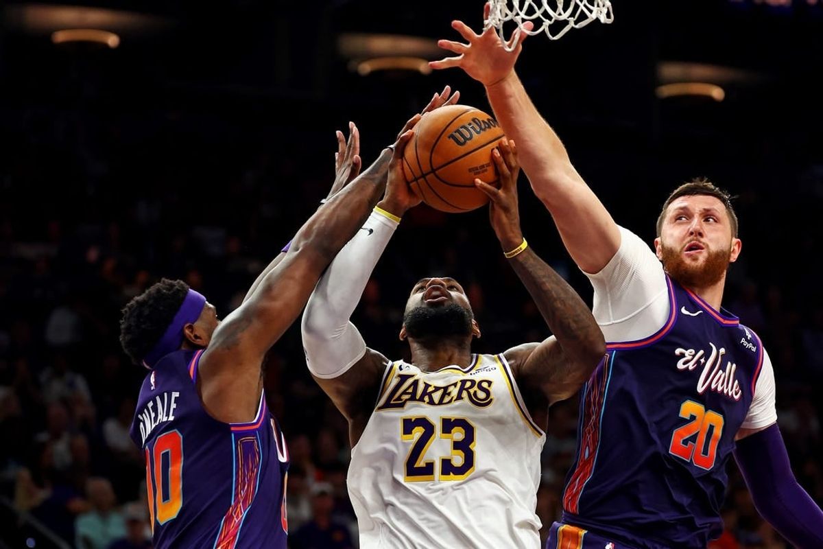 Feb 25, 2024; Phoenix, Arizona, USA; Los Angeles Lakers forward LeBron James (23) shoots the ball against Phoenix Suns forward Royce O'Neale (00) and center Jusuf Nurkic (20) during the fourth quarter at Footprint Center.
