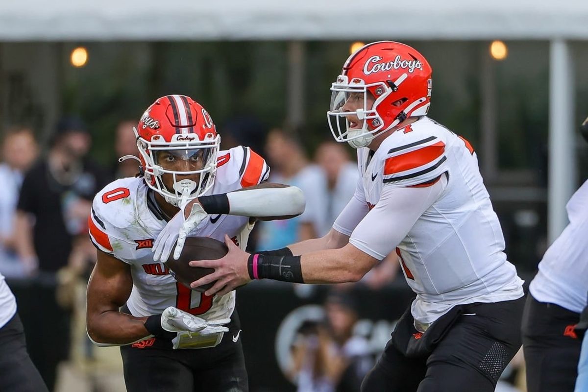 Nov 11, 2023; Orlando, Florida, USA; Oklahoma State Cowboys quarterback Alan Bowman (7) hands off to running back Ollie Gordon II (0) during the first quarter against the UCF Knights at FBC Mortgage Stadium.