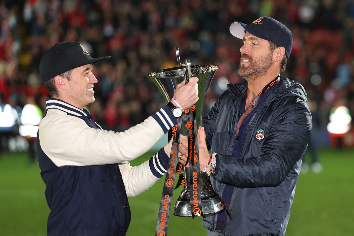 Los propietarios de Wrexham, Rob McElhenney y Ryan Reynolds, sostienen el Trofeo de la Liga Nacional Vanarama