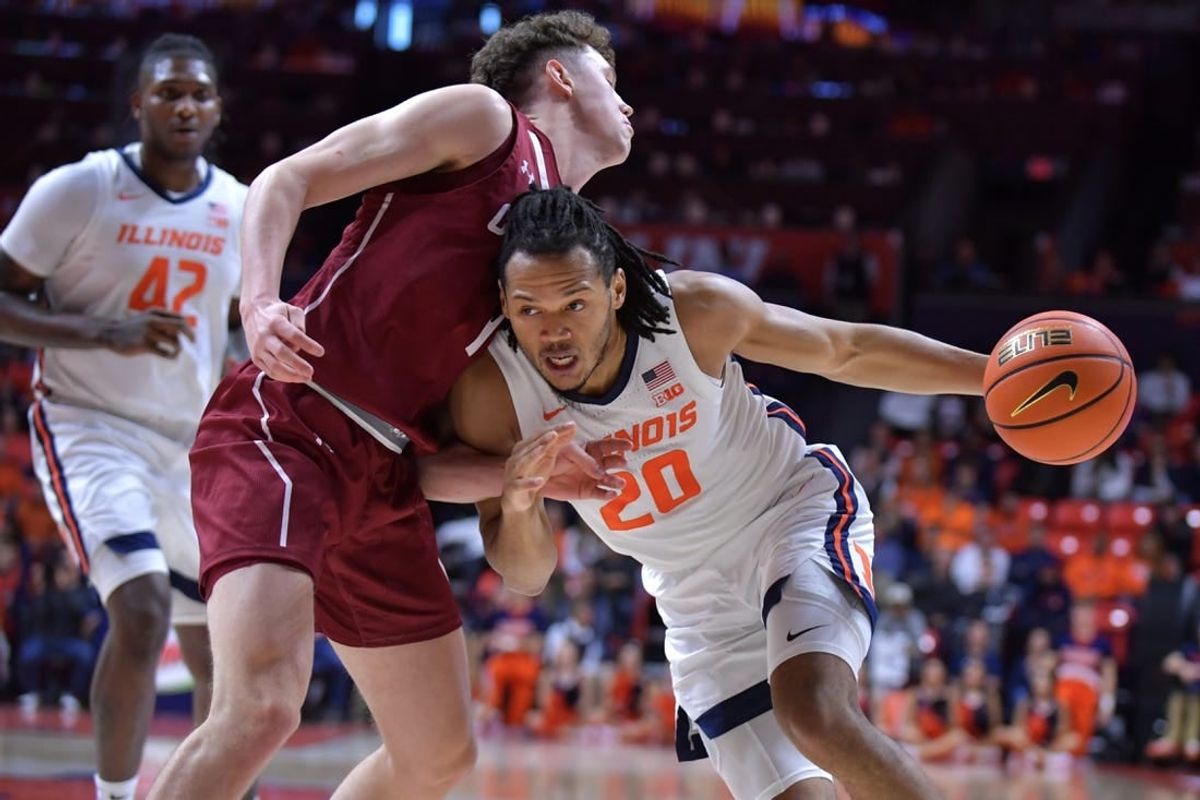 Dec 17, 2023; Champaign, Illinois, USA;  Illinois Fighting Illini forward Ty Rodgers (20) drives the ball against Colgate Raiders guard Brady Cummins (1) during the first half at State Farm Center.