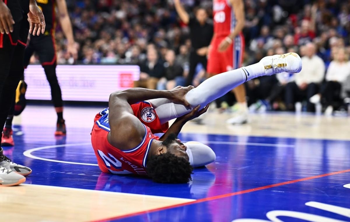 Dec 8, 2023; Philadelphia, Pennsylvania, USA; Philadelphia 76ers center Joel Embiid (21) grabs his knee after falling against the Atlanta Hawks in the fourth quarter at Wells Fargo Center.
