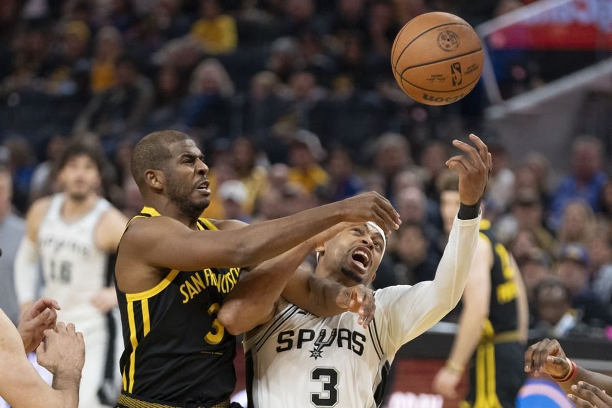 November 24, 2023; San Francisco, California, USA; Golden State Warriors guard Chris Paul (3, left) and San Antonio Spurs forward Keldon Johnson (3, right) fight for the rebound during the first quarter at Chase Center.