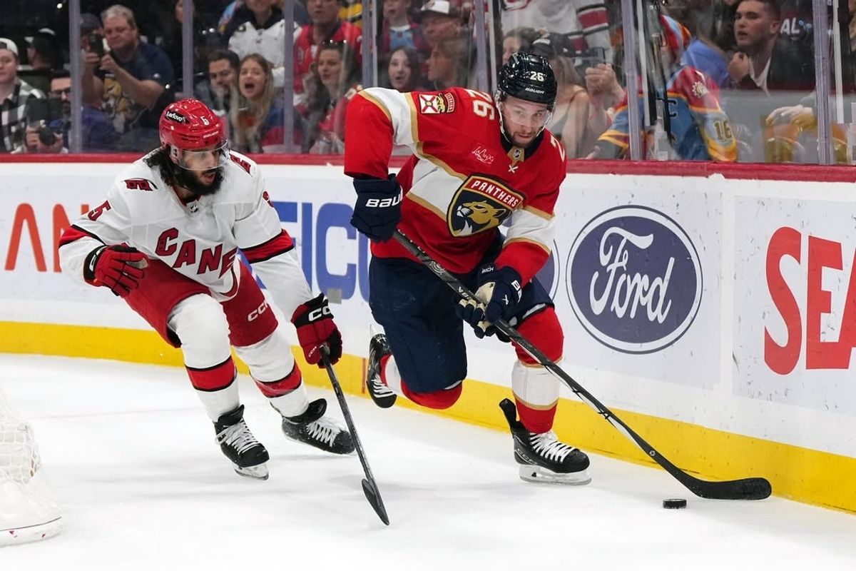 Nov 10, 2023; Sunrise, Florida, USA; Florida Panthers defenseman Uvis Balinskis (26) controls the puck away from Carolina Hurricanes defenseman Jalen Chatfield (5) during the second period at Amerant Bank Arena.