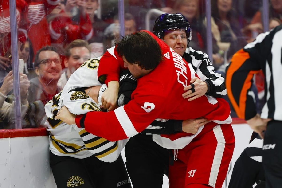 Dec 31, 2023; Detroit, Michigan, USA; Detroit Red Wings defenseman Ben Chiarot (8) scuffles with Boston Bruins center Morgan Geekie (39) while linesman Derek Amell (75) tries to separate them during the first period of the game between the Boston Bruins and the Detroit Red Wings at Little Caesars Arena.
