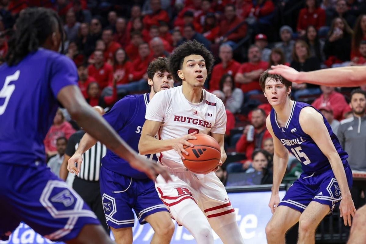 Dec 30, 2023; Piscataway, New Jersey, USA; Rutgers Scarlet Knights guard Derek Simpson (0) drives to the basket in front of Stonehill Skyhawks guard Josh Mack (5) and guard John O'Reilly III (15) during the first half at Jersey Mike's Arena.