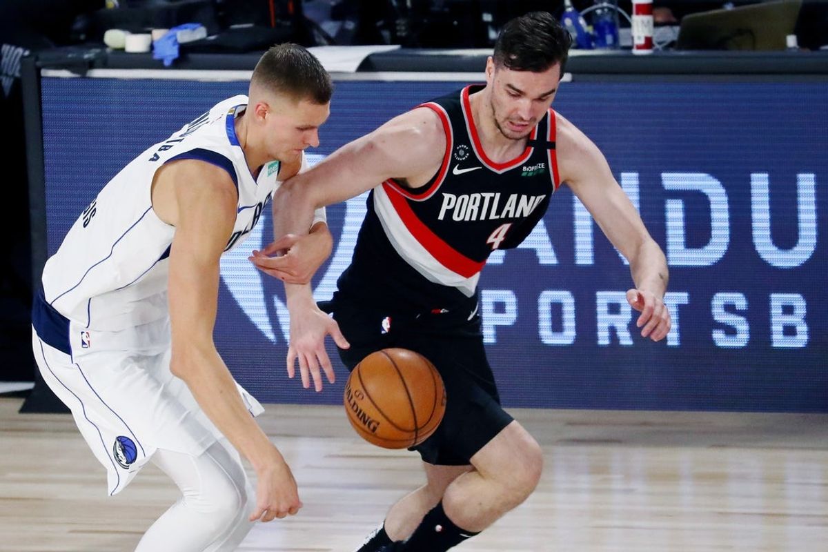Aug 11, 2020; Lake Buena Vista, Florida, USA; Dallas Mavericks forward Kristaps Porzingis (6) and Portland Trail Blazers forward Mario Hezonja (44) battle for the ball during the second half of a NBA game at The Field House. Mandatory Credit: Kim Klement-Imagn Images