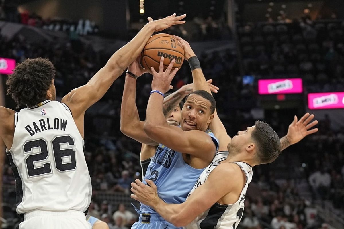 Nov 18, 2023; San Antonio, Texas, USA; Memphis Grizzlies guard Desmond Bane (22) looks to pass the ball while defended by San Antonio Spurs forwards Dom Barlow (26) and Doug McDermott (17) during the second half at Frost Bank Center.