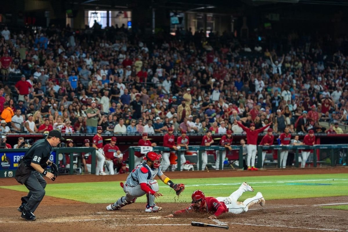 Apr 14, 2024; Phoenix, Arizona, USA; Arizona Diamondbacks infielder Christian Walker (11) slides in to score ahead of the tag of St. Louis Cardinals catcher Ivan Herrera (7) in the fifth inning during a game at Chase Field.