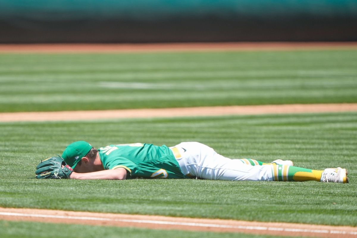 Jun 13, 2021; Oakland, California, USA;  Oakland Athletics starting pitcher Chris Bassitt (40) lays on the grass after attempting to make a play at home during the second inning against the Kansas City Royals at RingCentral Coliseum. Mandatory Credit: Stan Szeto-Imagn Images