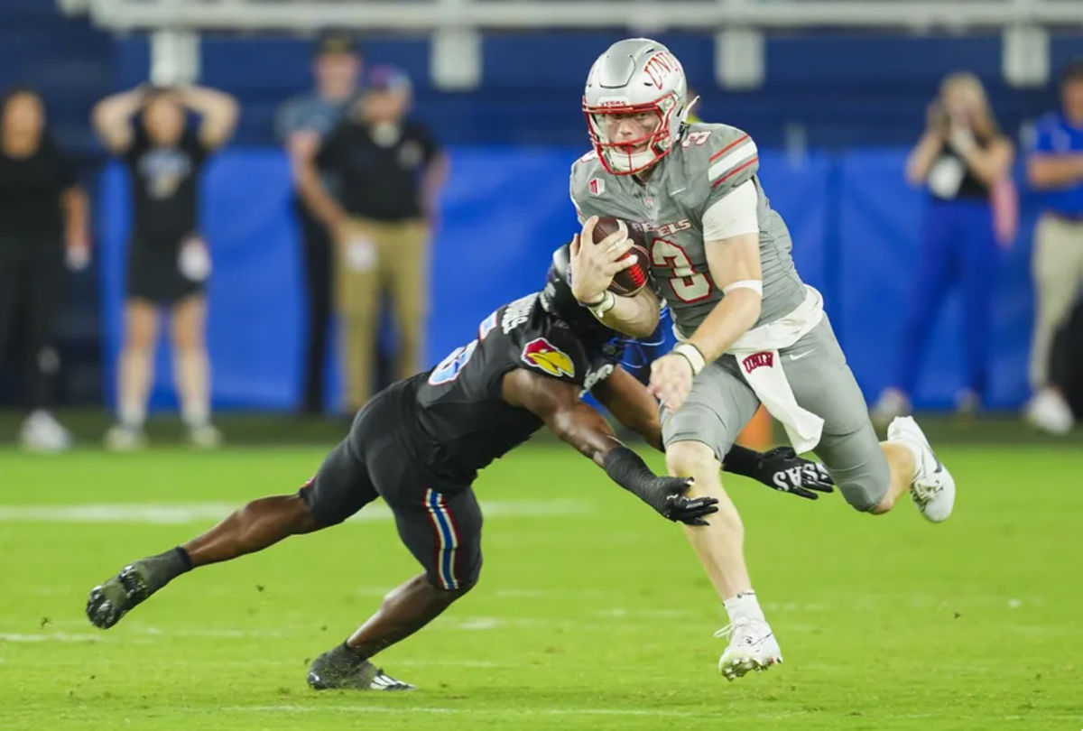 13 de septiembre de 2024; Kansas City, Kansas, EE. UU.; El mariscal de campo de los UNLV Rebels, Matthew Sluka (3), corre con el balón contra el safety de los Kansas Jayhawks, O.J. Burroughs (5), durante la segunda mitad en el Children's Mercy Park. Crédito obligatorio: Jay Biggerstaff-Imagn Images