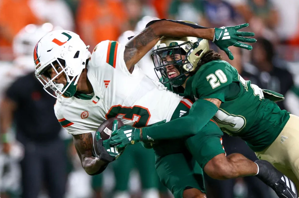 21 de setembro de 2024; Tampa, Flórida, EUA; O wide receiver do Miami Hurricanes Jacolby George (3) é derrubado pelo cornerback do South Florida Bulls Brent Austin (20) no primeiro quarto no Raymond James Stadium. Crédito obrigatório: Nathan Ray Seebeck-Imagn Images