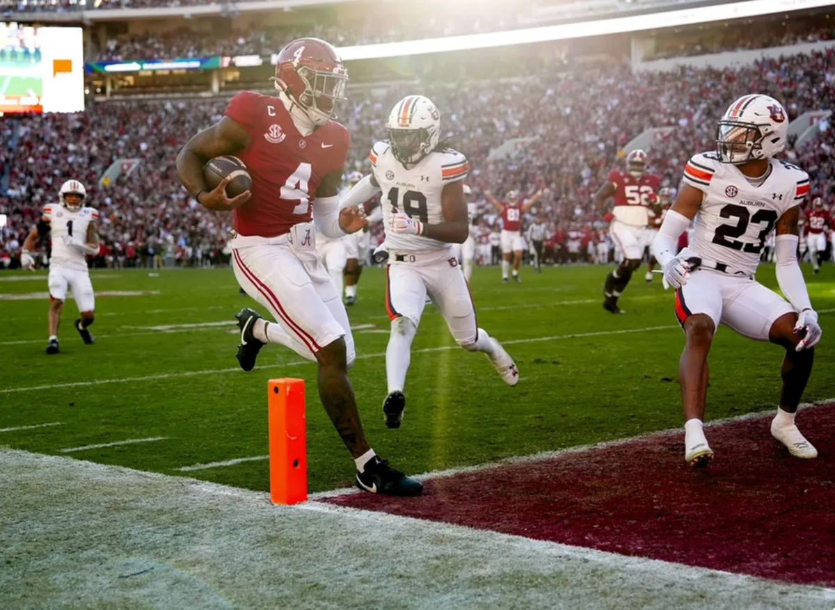 30 de noviembre de 2024; Tuscaloosa, Alabama, EE. UU.; El mariscal de campo de Alabama Crimson Tide, Jalen Milroe (4), corre para anotar un touchdown contra el safety de Auburn, Kaleb Harris (18), durante la primera mitad en el Bryant-Denny Stadium. Crédito obligatorio: Gary Cosby Jr.-Imagn Images