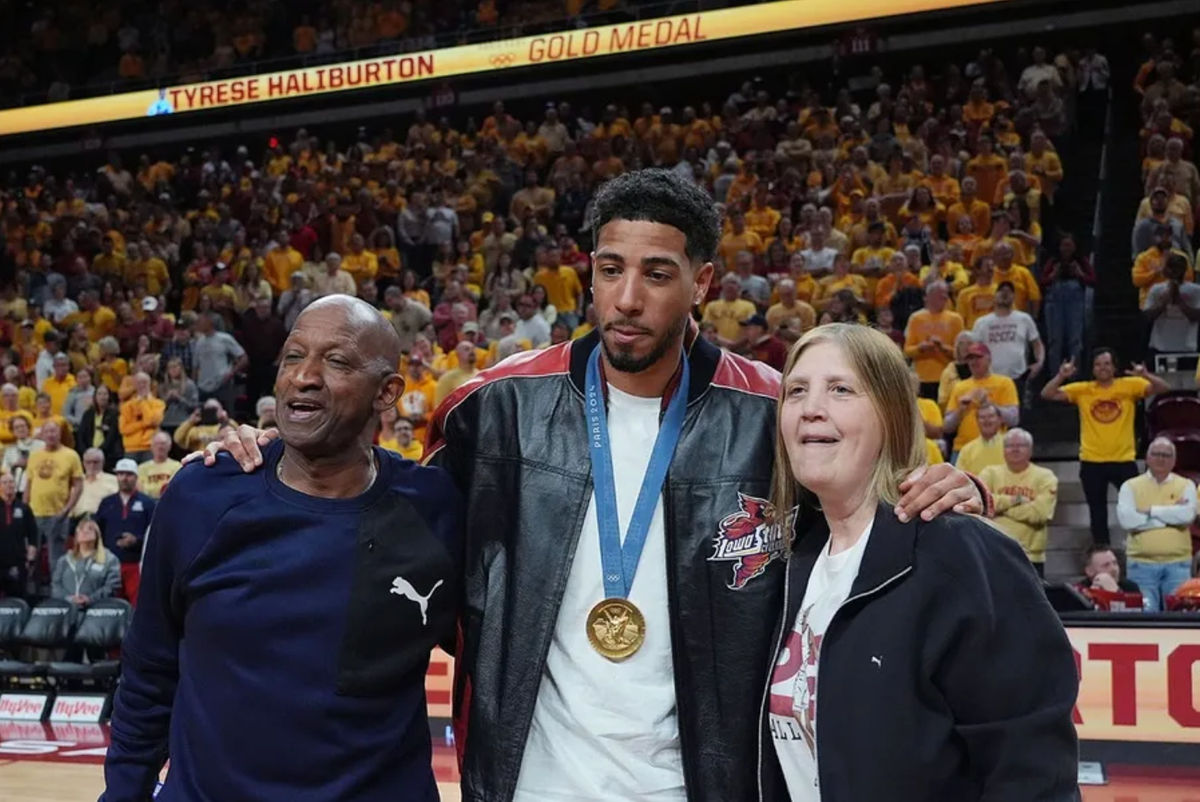El ex base de Iowa State e Indiana Packer, Tyrese Haliburton, sostiene a sus padres, John y Brenda Haliburton, mientras revela su pancarta de oro olímpica de 24 durante el entretiempo del enfrentamiento de baloncesto masculino de Cyclones y Wildcats en el Hilton Coliseum el sábado 1 de marzo de 2025 en Ames, Iowa.