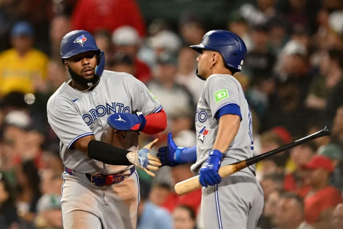 Jun 27, 2025; Boston, Massachusetts, USA; Toronto Blue Jays first baseman Vladimir Guerrero Jr. (27) high-fives second baseman Andres Gimenez (0) after scoring a run against the Boston Red Sox during the eighth inning at Fenway Park. Mandatory Credit: Brian Fluharty-Imagn Images