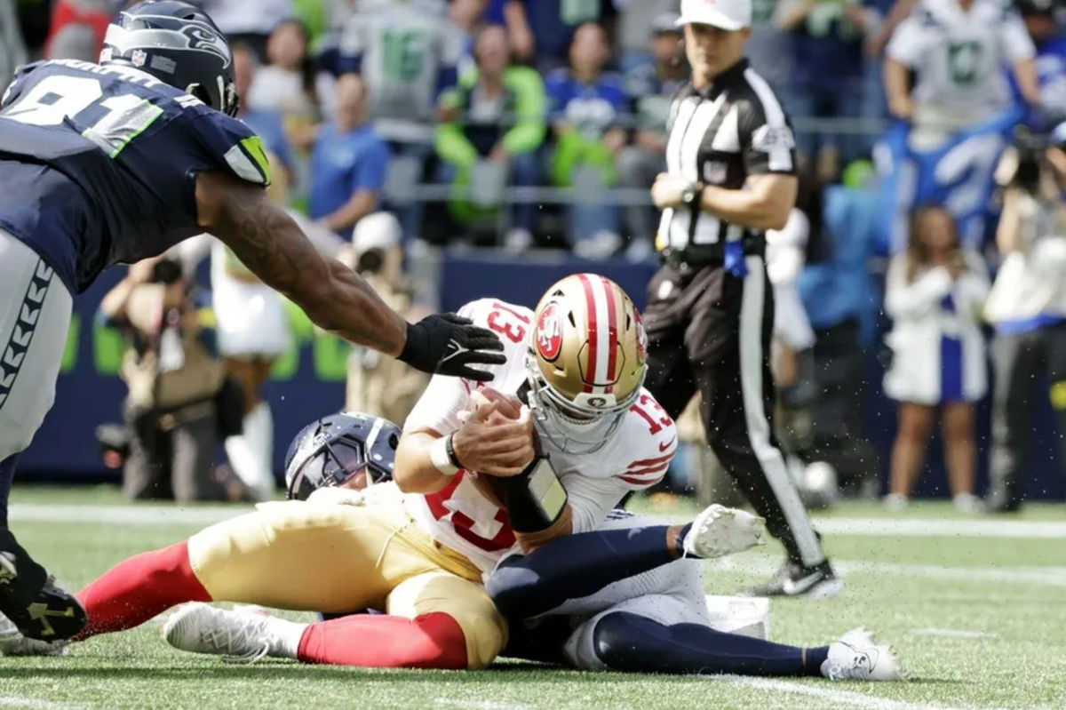 Sep 7, 2025; Seattle, Washington, USA; San Francisco 49ers quarterback Brock Purdy (13) is tackled during the first half against the Seattle Seahawks at Lumen Field. Mandatory Credit: Joe Nicholson-Imagn Images