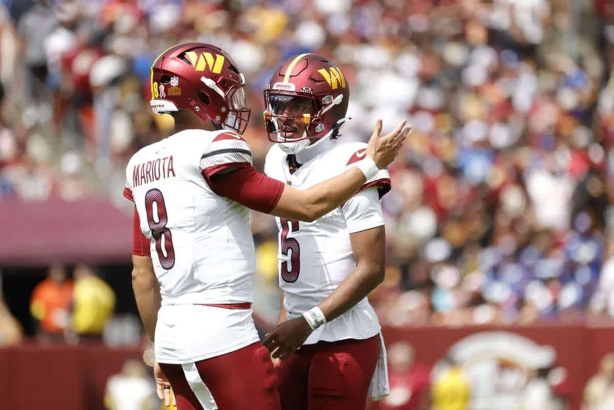 Sep 7, 2025; Landover, Maryland, USA; Washington Commanders quarterback Jayden Daniels (5) talks to Commanders quarterback Marcus Mariota (8) on the field during the first quarter against the New York Giants at Northwest Stadium. Mandatory Credit: Amber Searls-Imagn Images