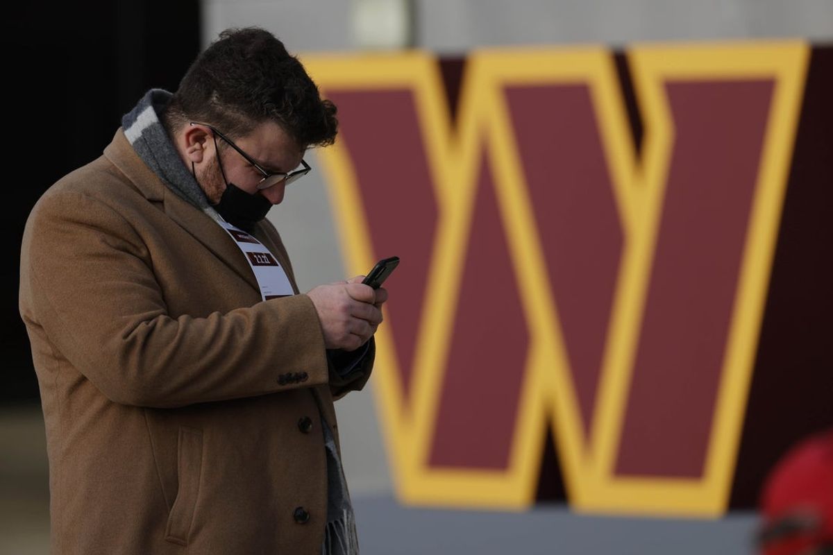 Feb 2, 2022; Landover, MD, USA; A member of the press tweets in front of a new team logo after the announcement during a press conference revealing the Washington Commanders as the new name for the formerly named Washington Football Team at FedEx Field. Mandatory Credit: Geoff Burke-Imagn Images