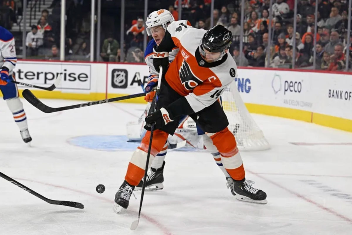 12 de novembro de 2025; Filadélfia, Pensilvânia, EUA; O atacante do Philadelphia Flyers, Sean Couturier (14), e o defensor do Edmonton Oilers, Ty Emberson (49), disputam o disco durante o primeiro período na Xfinity Mobile Arena. Crédito obrigatório: Eric Hartline-Imagn Images
