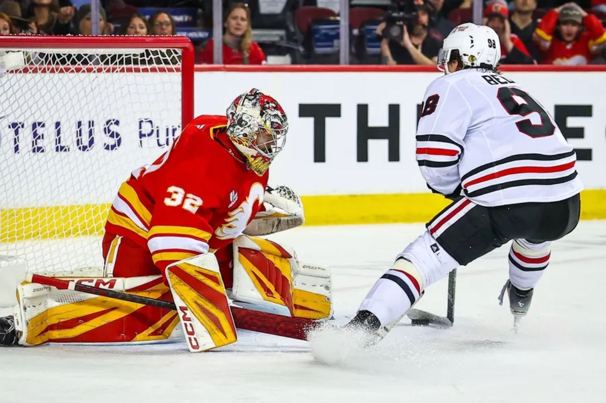 7 de noviembre de 2025; Calgary, Alberta, Canadá; El centro de los Chicago Blackhawks, Connor Bedard (98), anota contra el portero de los Calgary Flames, Dustin Wolf (32), durante el tercer periodo en el Scotiabank Saddledome. Crédito obligatorio: Sergei Belski-Imagn Images.