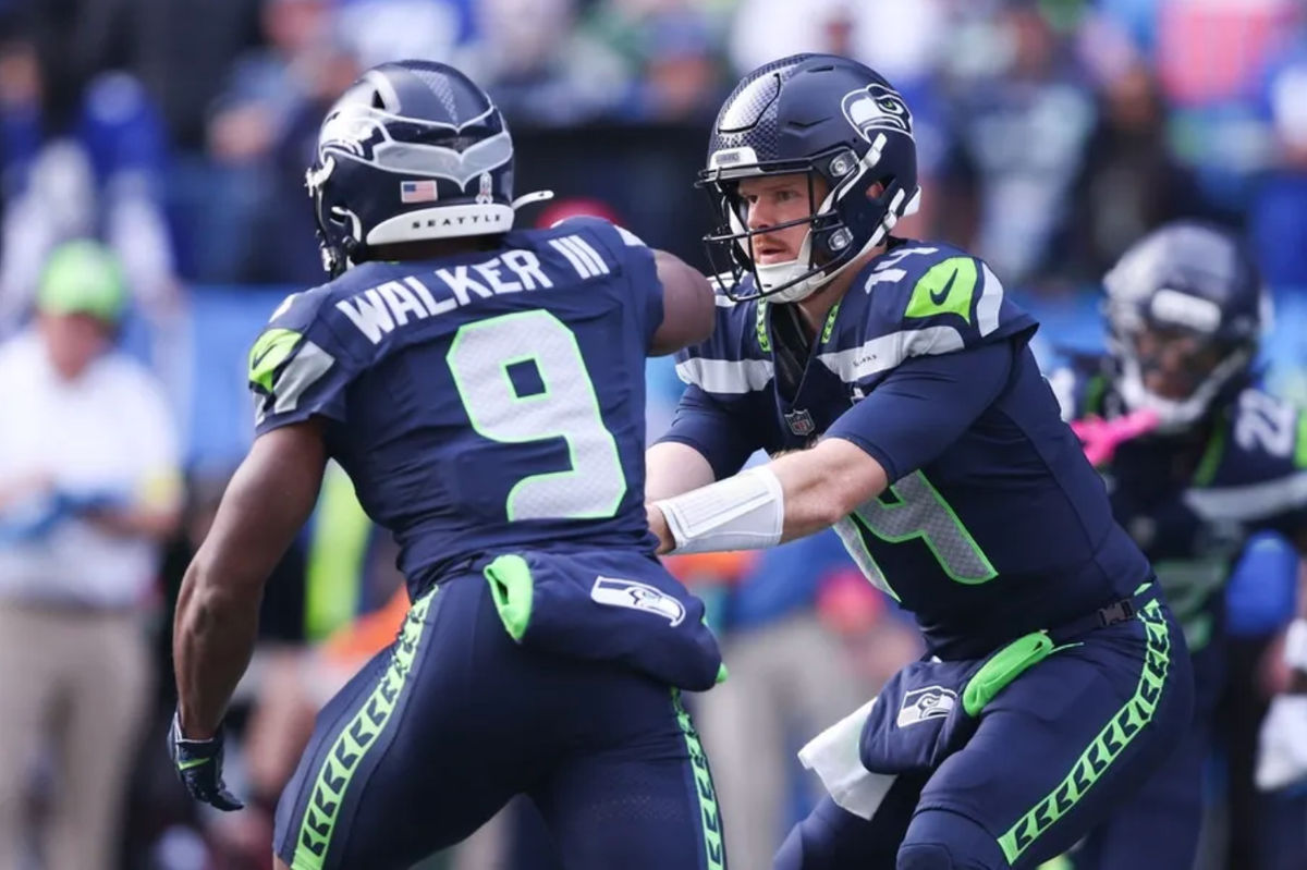 9 de novembro de 2025; Seattle, Washington, EUA; O quarterback do Seattle Seahawks, Sam Darnold (14), passa a bola para o running back do Seattle Seahawks, Kenneth Walker III (9), durante o primeiro quarto no Lumen Field. Crédito obrigatório: Kevin Ng-Imagn Images
