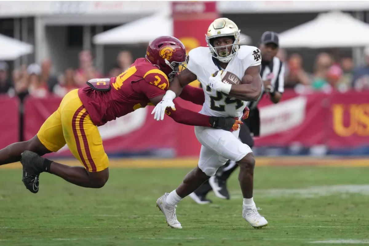 30 de noviembre de 2024; Los Ángeles, California, EE. UU.; El corredor de Notre Dame Fighting Irish, Jadarian Price (24), acarrea el balón contra el ala defensiva de los Southern California Trojans, Braylan Shelby (34), en la primera mitad en el United Airlines Field del Los Angeles Memorial Coliseum. Crédito obligatorio: Kirby Lee-Imagn Images
