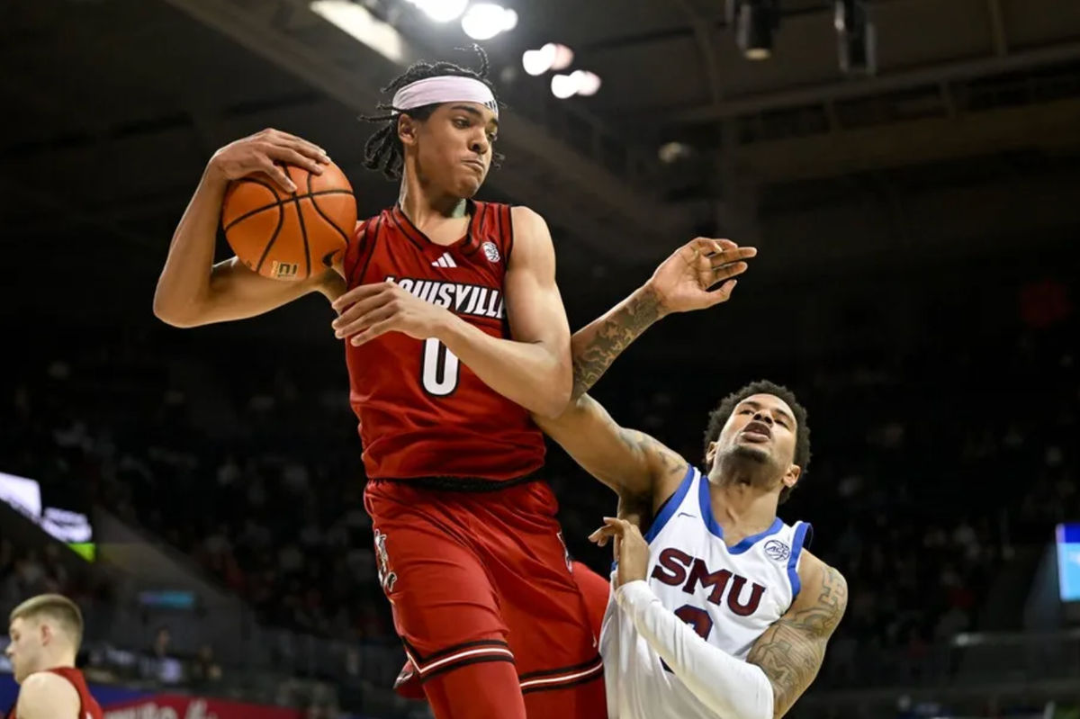 Feb 17, 2026; Dallas, Texas, USA; Louisville Cardinals guard Mikel Brown Jr. (0) grabs a rebound in front of SMU Mustangs forward Corey Washington (3) during the second half at Moody Coliseum. Mandatory Credit: Jerome Miron-Imagn Images