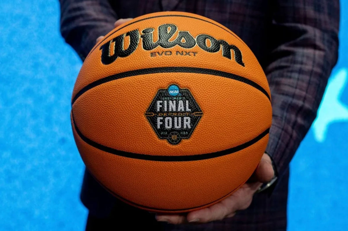 Dave Beachnau, CEO of the Detroit Local Organizing Committee, stands on stage holding a basketball featuring the newly unveiled logo for the 2027 NCAA Men’s Final Four during a press conference inside Ford Field in Detroit on Friday, Dec. 19, 2025.