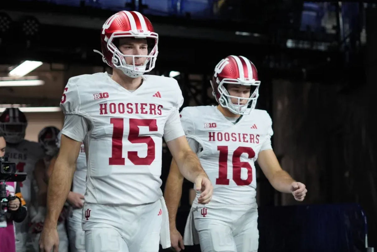 6 de dezembro de 2025; Indianápolis, IN, EUA; O quarterback do Indiana Hoosiers, Fernando Mendoza (15), e o quarterback Alberto Mendoza (16) entram em campo para o aquecimento antes do jogo do campeonato Big Ten de 2025 contra o Ohio State Buckeyes no Lucas Oil Stadium. Crédito obrigatório: Aaron Doster-Imagn Images