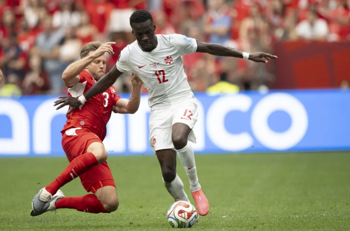 24 de junho de 2026; Vancouver, Colúmbia Britânica, CAN; O atacante canadense Tani Oluwaseyi (12) controla a bola contra o zagueiro suíço Silvan Widmer (3) durante o segundo tempo de uma partida do Grupo B da Copa do Mundo FIFA de 2026 no BC Place Vancouver. Crédito obrigatório: Anne-Marie Sorvin-Imagn Images