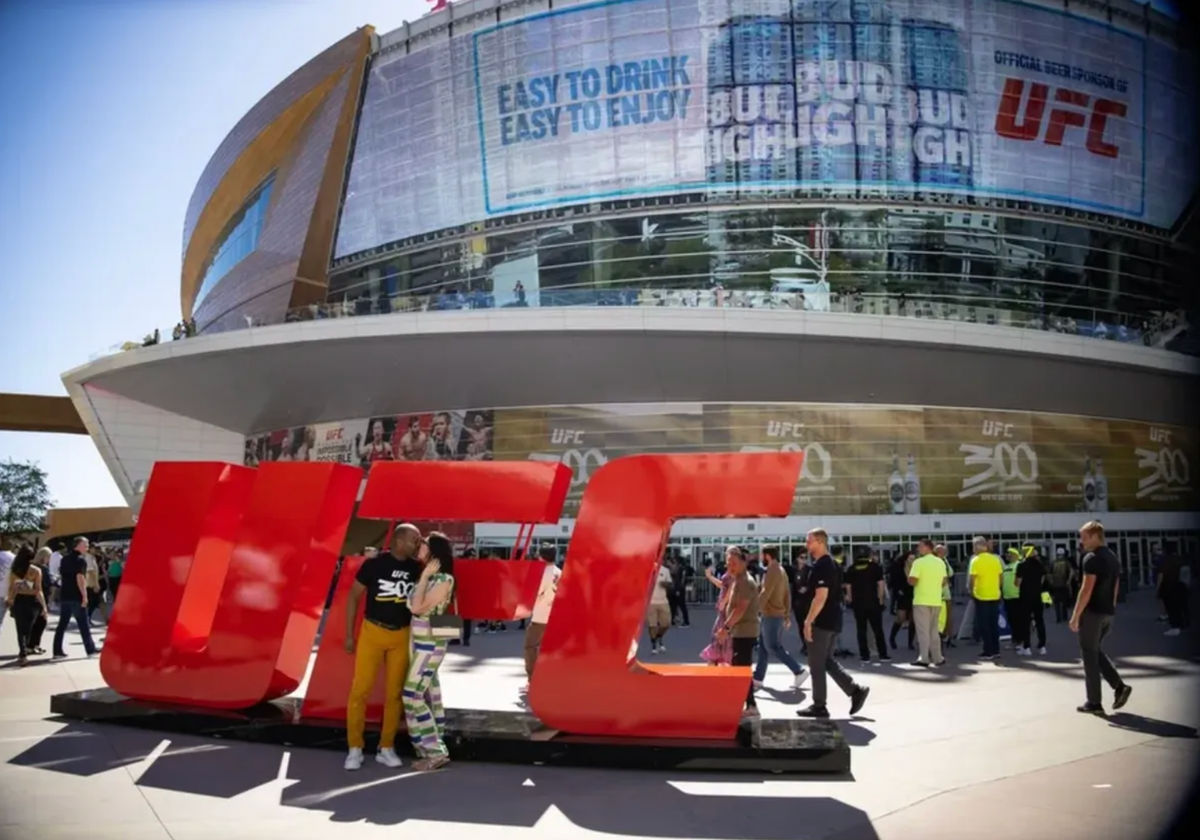 Apr 13, 2024; Las Vegas, Nevada, USA; A couple kisses in front of a UFC logo prior to UFC 300 at T-Mobile Arena. Mandatory Credit: Mark J. Rebilas-Imagn Images