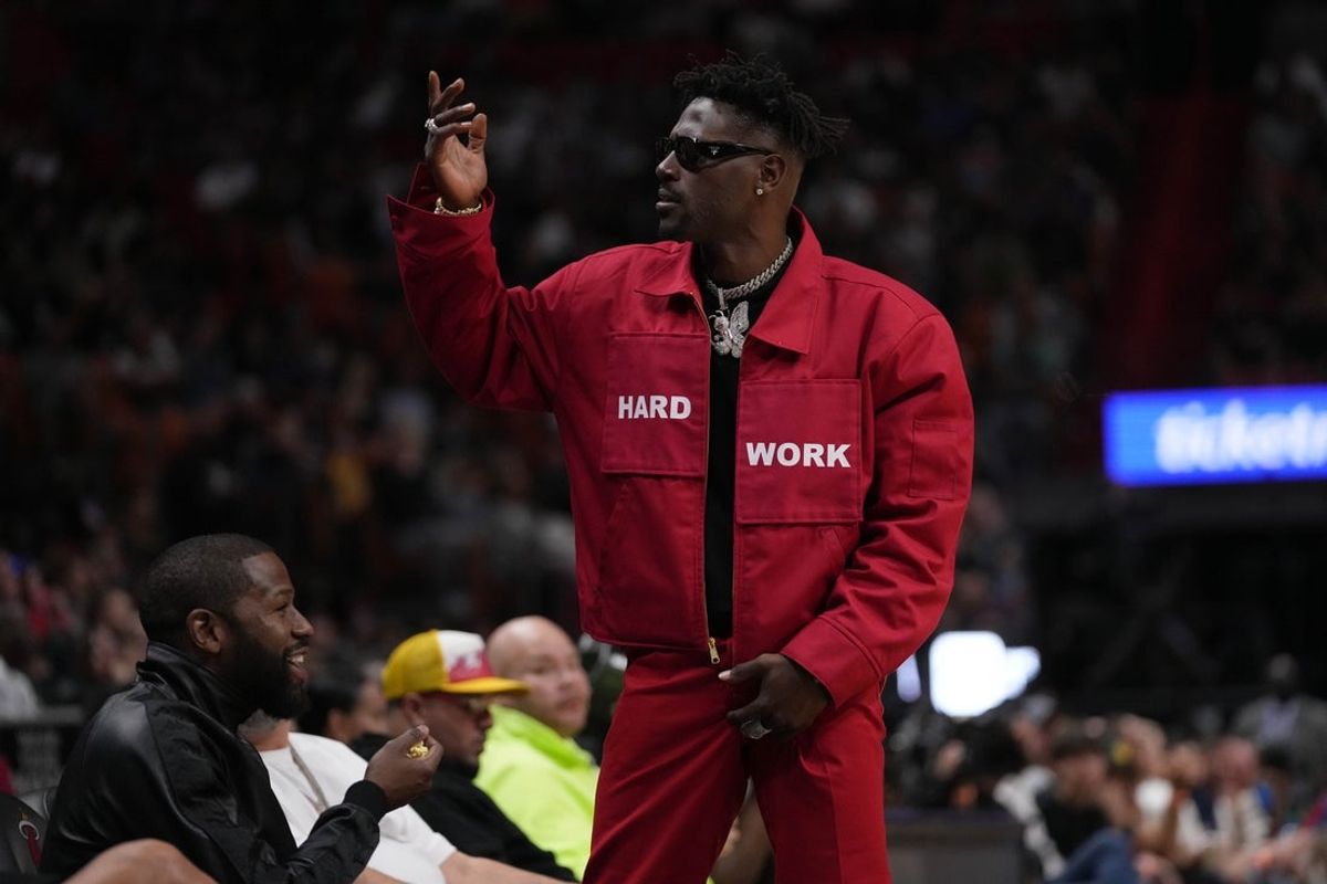 Mar 26, 2022; Miami, Florida, USA; Former NFL player Antonio Brown gestures to the fans while standing in from t of former professional boxer Floyd Mayweather Jr. during the second half between the Miami Heat and the Brooklyn Nets at FTX Arena. Mandatory Credit: Jasen Vinlove-Imagn Images