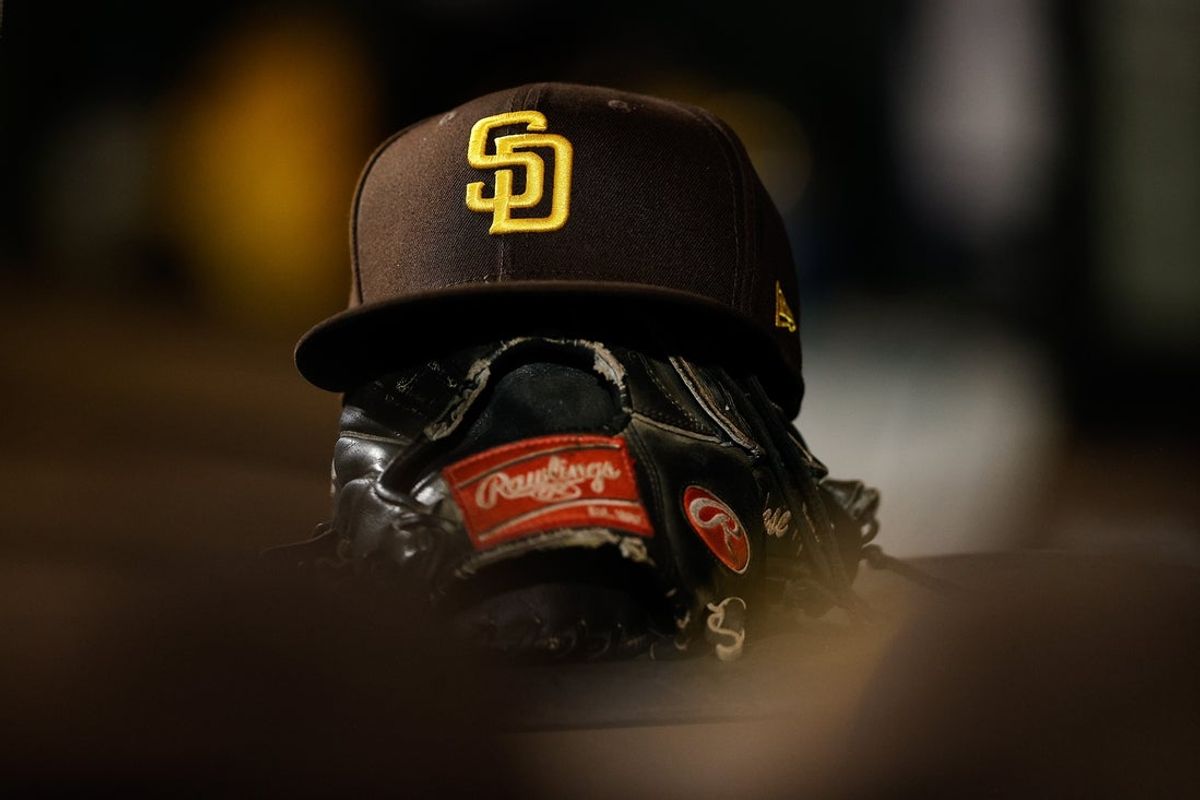 Jun 17, 2022; Denver, Colorado, USA; A detail view of a San Diego Padres hat on a glove in the dugout in the ninth inning against the Colorado Rockies at Coors Field. Mandatory Credit: Isaiah J. Downing-Imagn Images