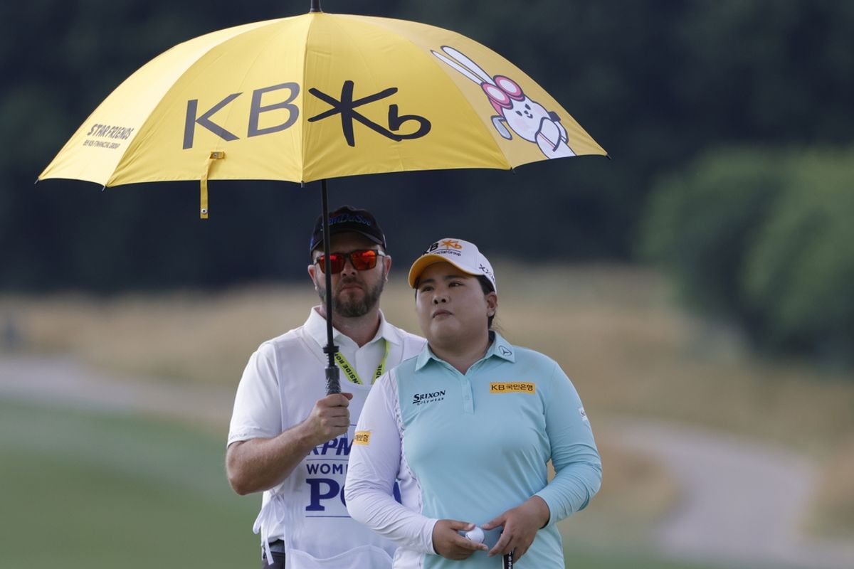 Jun 24, 2022; Bethesda, Maryland, USA; Inbee Park (R) stands under an umbrella held by caddie Brad Beecher (L) on the third green during the second round of the KPMG Women's PGA Championship golf tournament. Mandatory Credit: Geoff Burke-Imagn Images