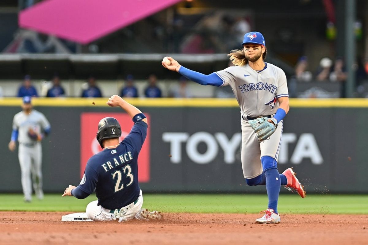 Jul 7, 2022; Seattle, Washington, USA; Toronto Blue Jays shortstop Bo Bichette (11) throws the ball to first base after the force out on Seattle Mariners designated hitter Ty France (23) during the first inning at T-Mobile Park. Mandatory Credit: Steven Bisig-Imagn Images