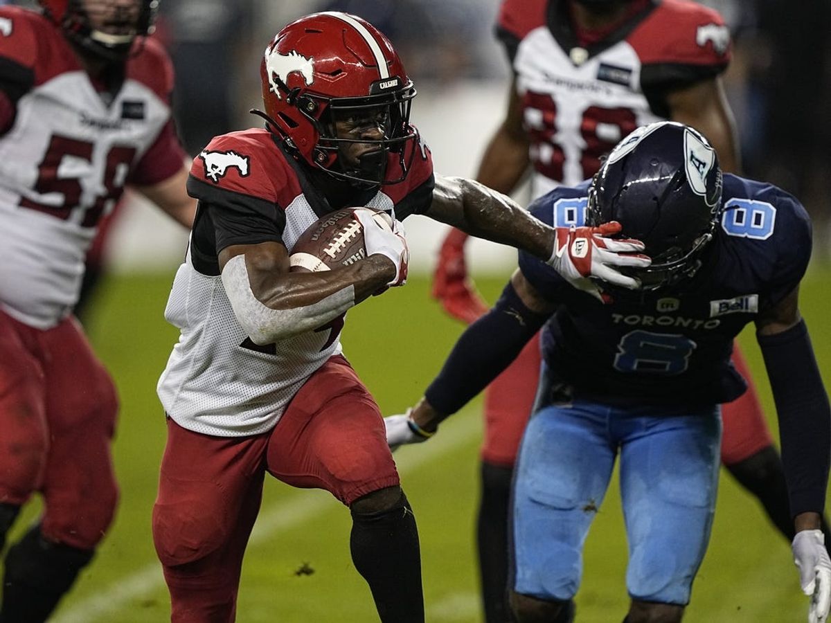 Aug 20, 2022; Toronto, Ontario, CAN; Calgary Stampeders wide receiver Shawn Bane Jr. (14) straight arms Toronto Argonauts defensive back DaShaun Amos (8) during the second half at BMO Field. Mandatory Credit: John E. Sokolowski-USA TODAY Sports
