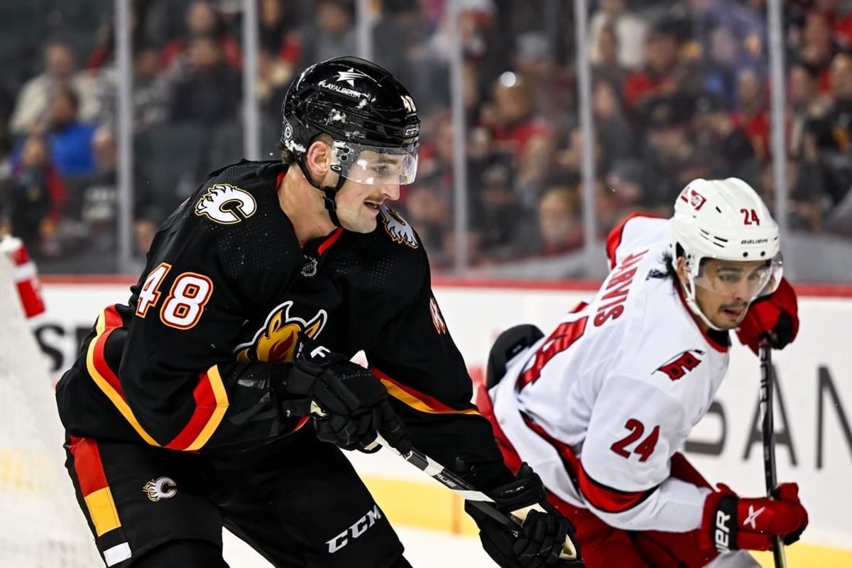 Dec 7, 2023; Calgary, Alberta, CAN; Calgary Flames defenseman Dennis Gilbert (48) competes for the puck against Carolina Hurricanes center Seth Jarvis (24) during the second period of a game at Scotiabank Saddledome.