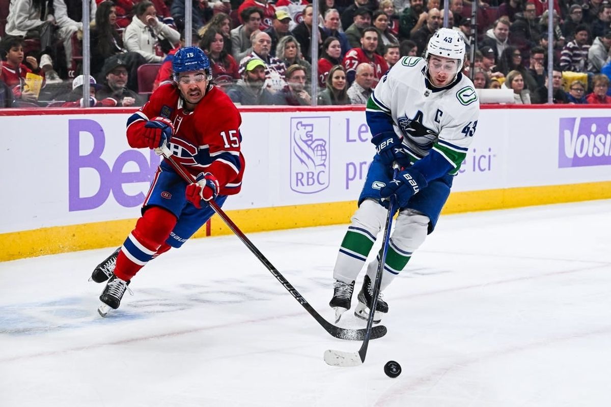 Nov 12, 2023; Montreal, Quebec, CAN; Vancouver Canucks defenseman Quinn Hughes (43) defends the puck against Montreal Canadiens center Alex Newhook (15) during the second period at Bell Centre.